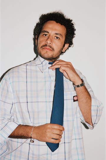 individual adjusting a tie while wearing a checkered shirt