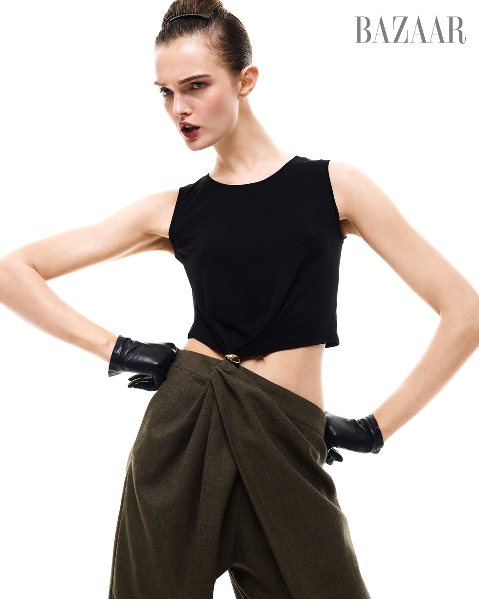 fashion model showcasing a black top and tailored olive green trousers