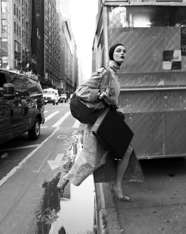 person in motion carrying a briefcase and a bag on a city street