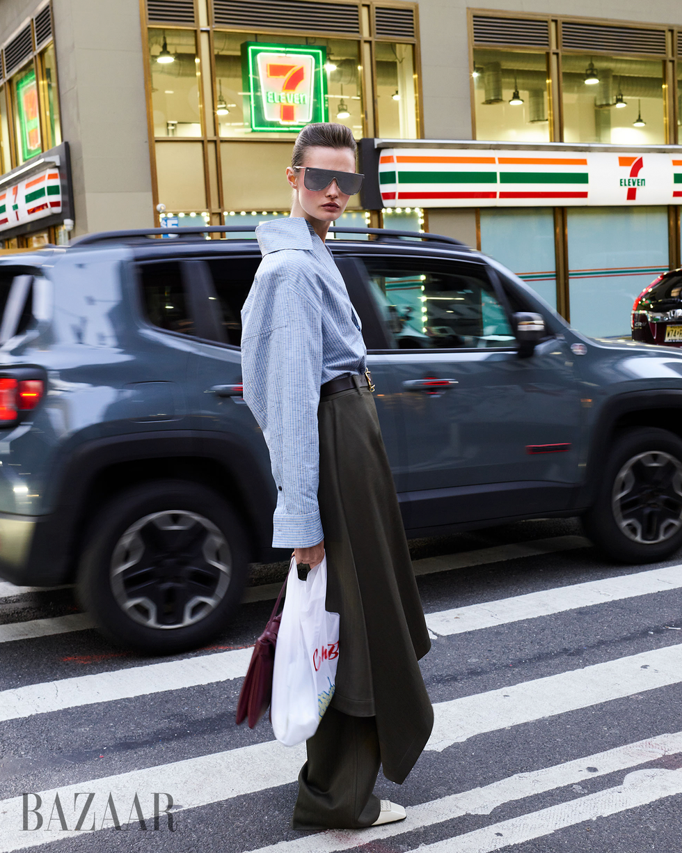 fashionable individual standing at a crosswalk in an urban setting