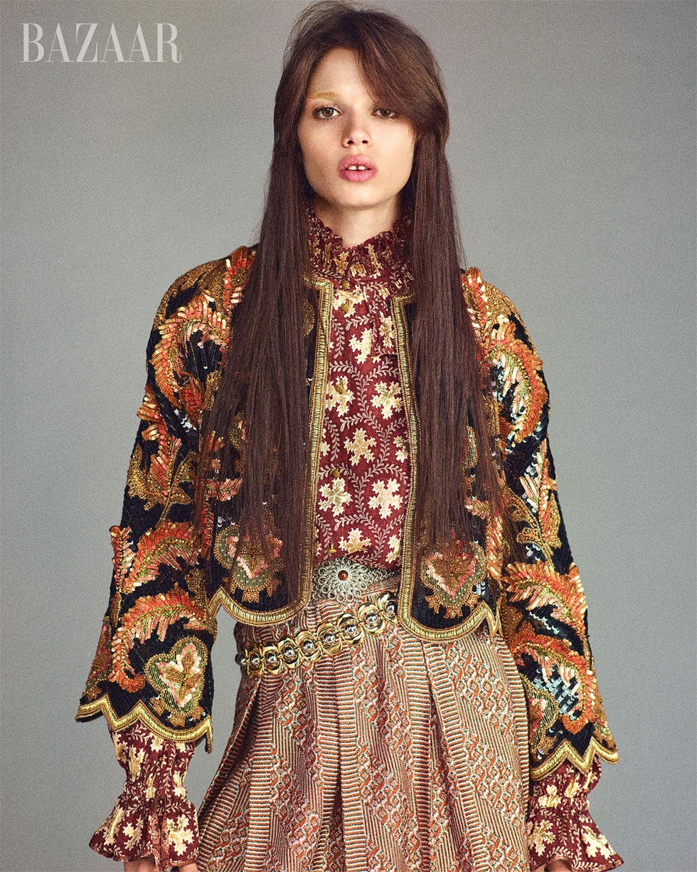 fashion model wearing a richly embroidered jacket and patterned skirt
