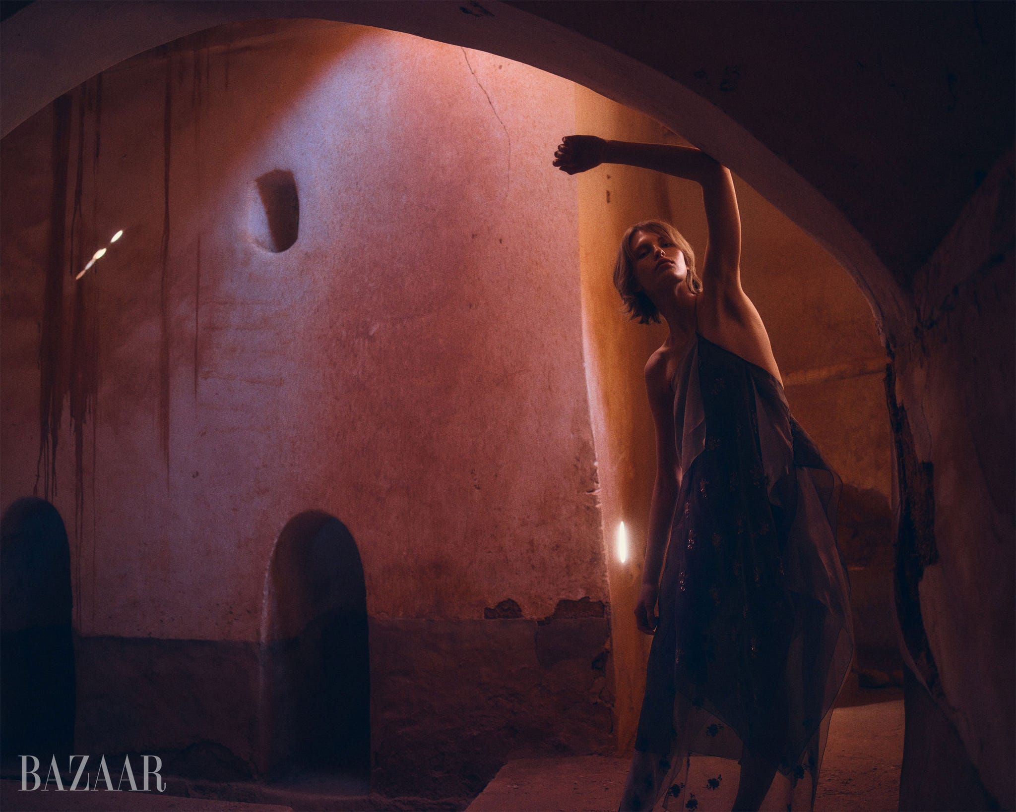a figure is striking a pose in a dimly lit textured space
