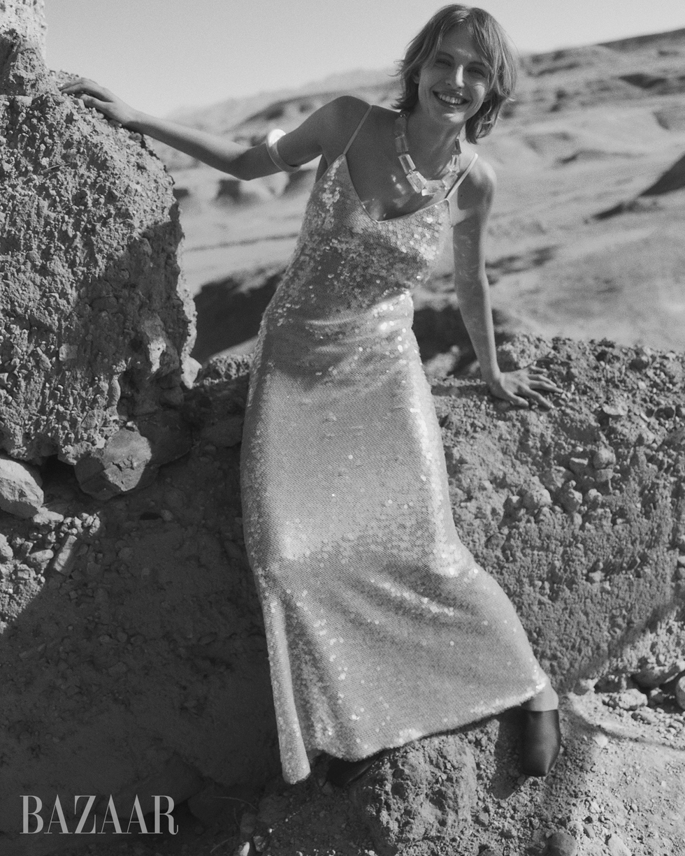 fashion model posing in a sequined dress against a rocky landscape