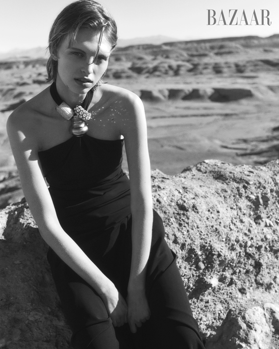fashion editorial featuring a model in a black dress with a bold necklace on rocky terrain