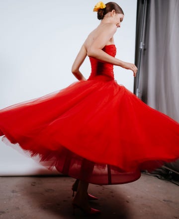 A model wearing a vibrant red dress that flares out as she spins