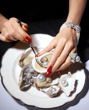 woman with red nail polish eating oysters with pearls inside