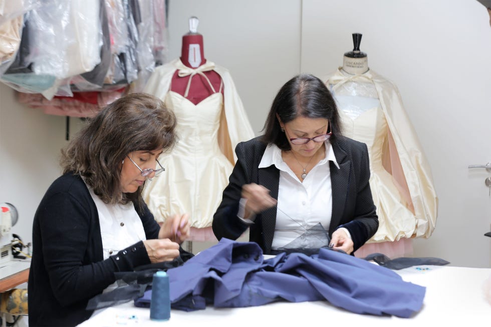 two women sewing garments in a fashion design workspace
