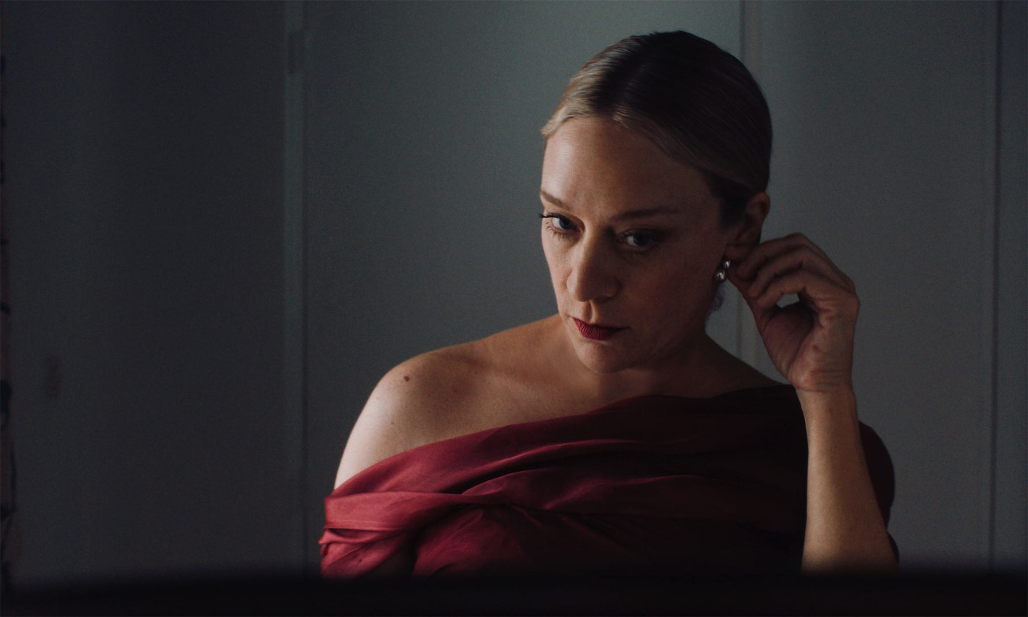 a person wearing a red garment appears to be adjusting their hair or clothing in a reflective surface