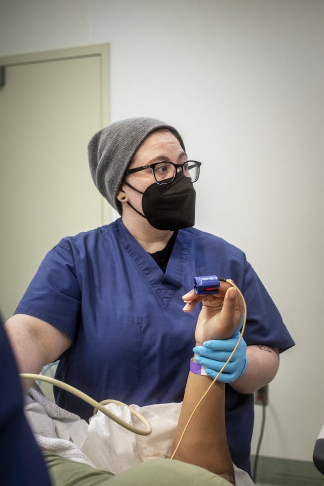 a nurse holds the hand of a patient during an abortion procedure