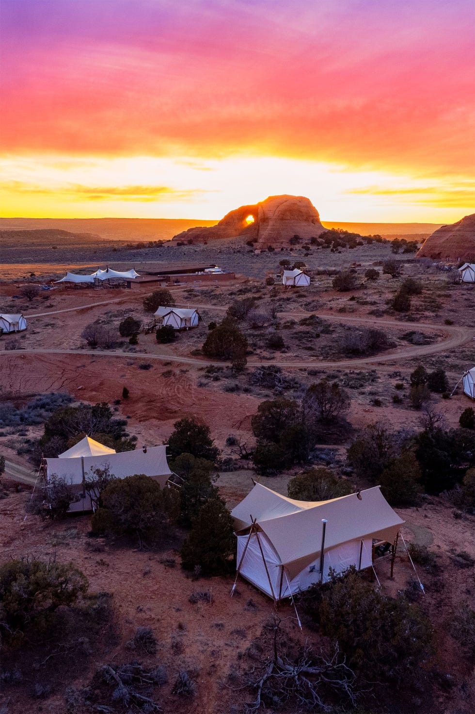 Glamping tents set in a desert landscape during sunset