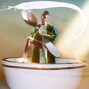 model holds giant spoon in tea cup