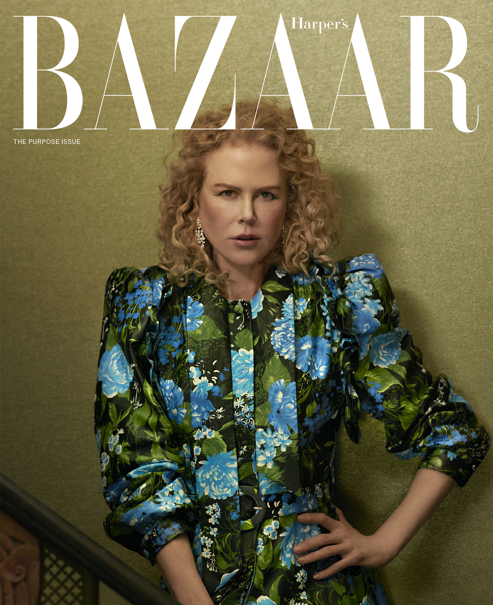 nicole poses in a green, blue, and black floral dress, diamond earrings, while leaning against a green wall, bazaar logo is at the top