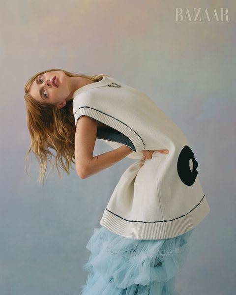 samara bends backwards in a tulle blue skirt and white sweater vest with black detailing