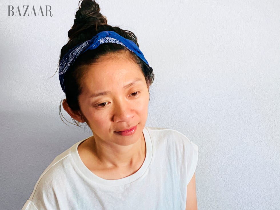 chloe sits against white wall in white t shirt and blue headband looking off camera