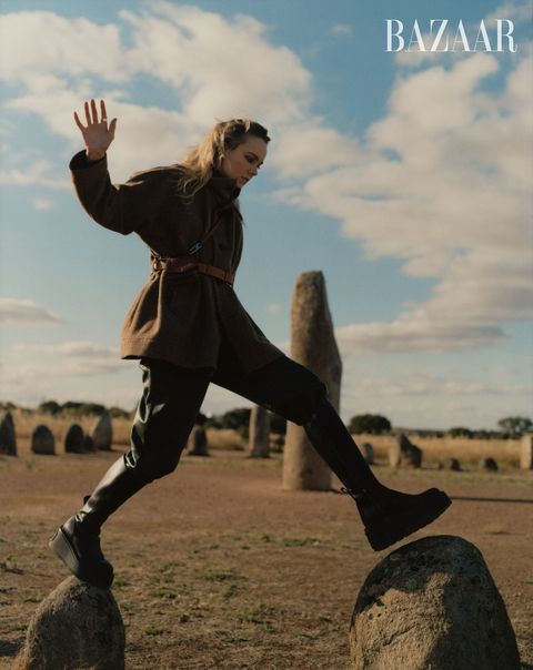 woman stepping on rocks in brown jacket black platform boots