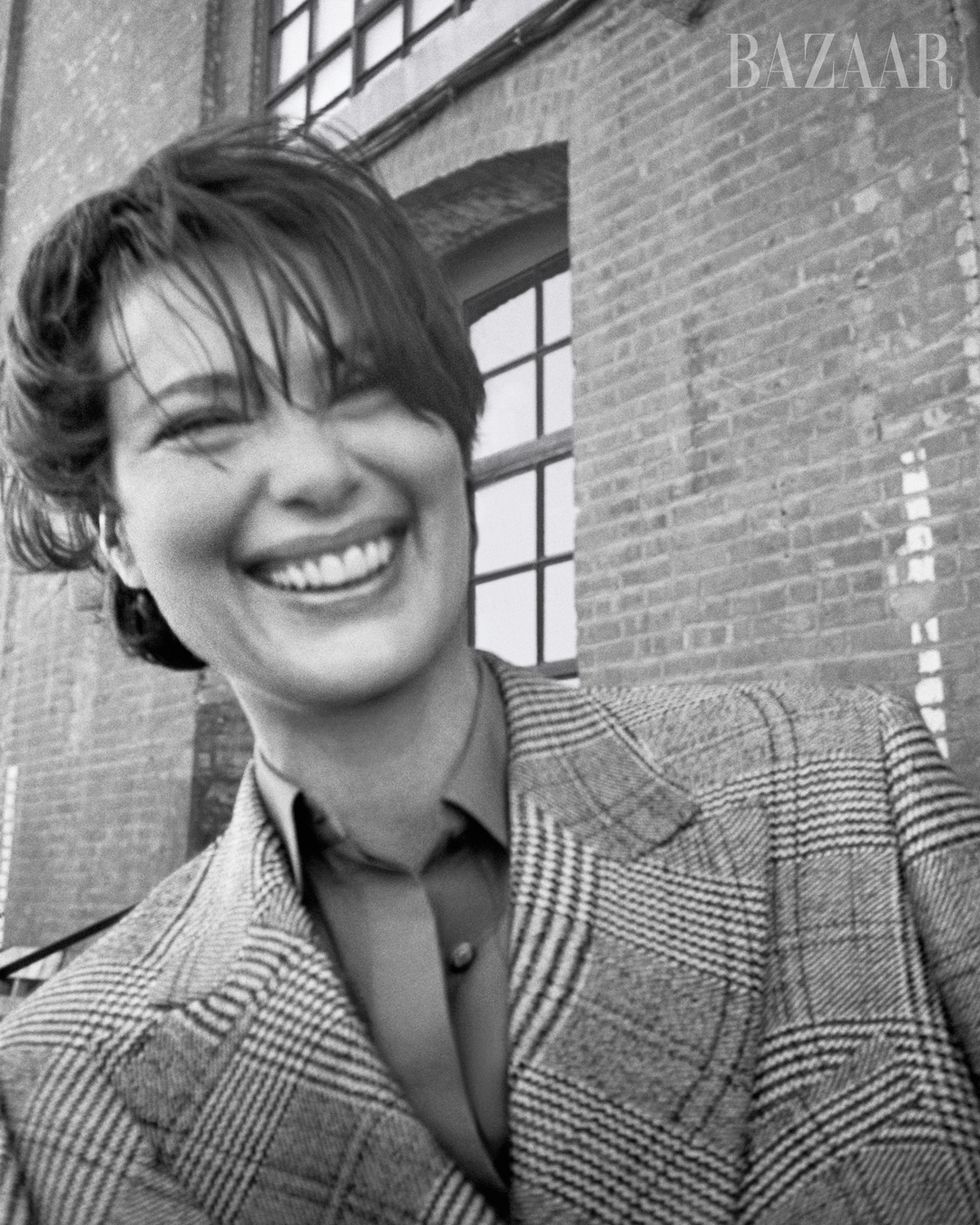 black and white headshot of woman smiling in a cross hatch suit jacket