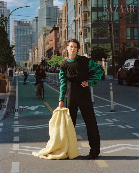 woman in black jumpsuit with green longsleeve undershirt and yellow jacket