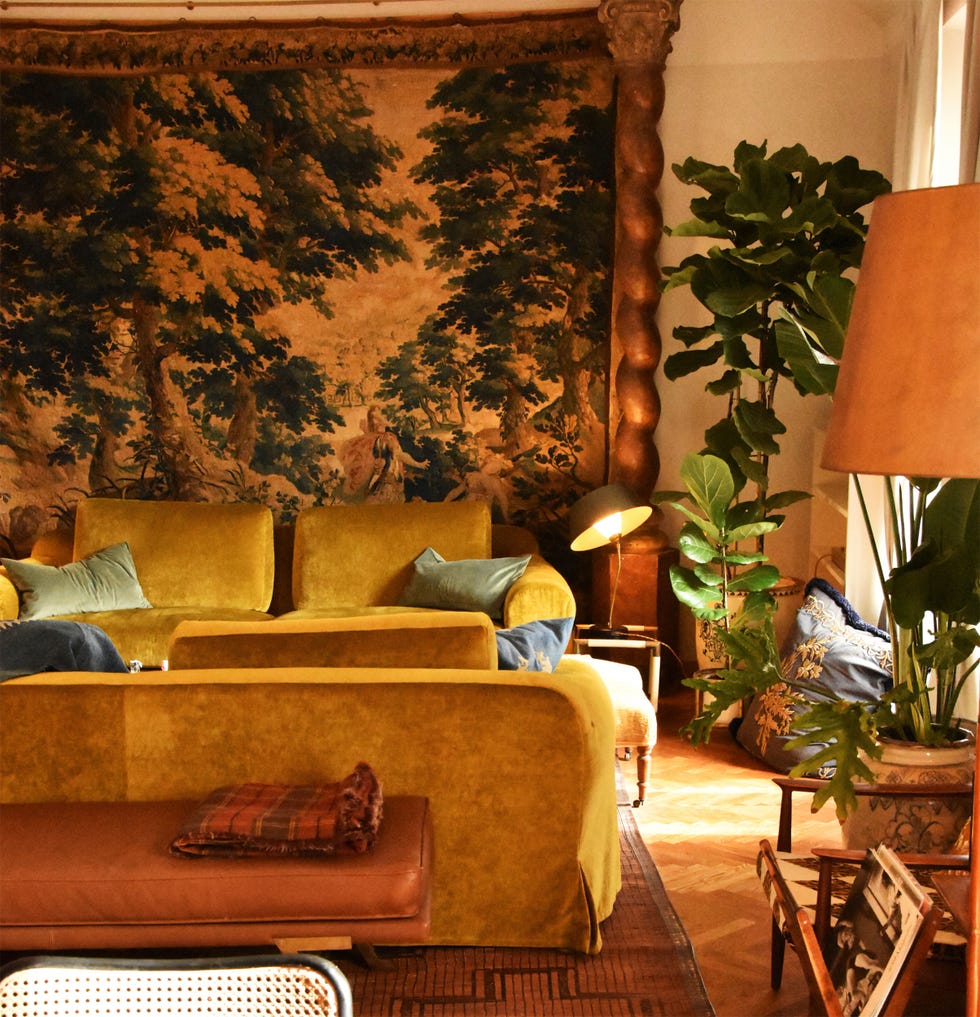 living room with yellow sofas plants and a decorative wall tapestry