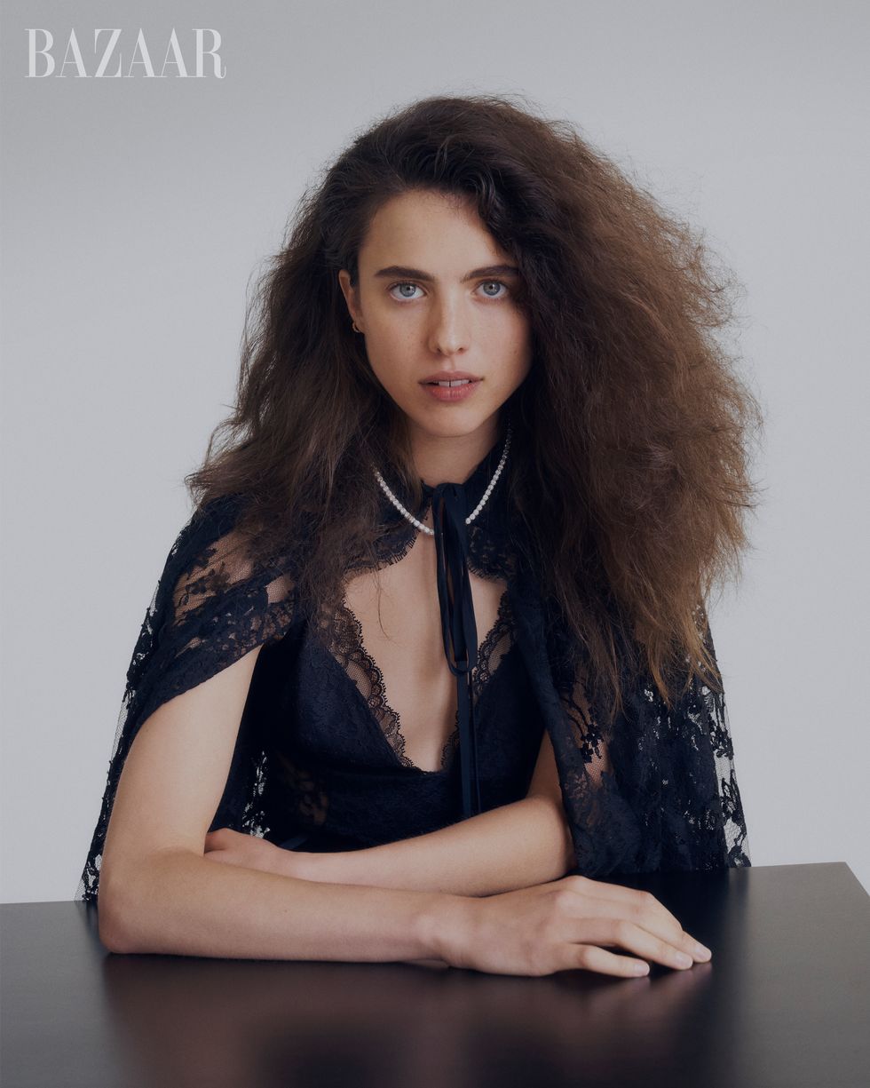 headshot of woman in navy lace cape with hands on black table