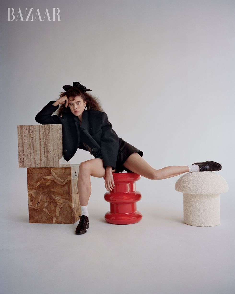 woman in black blazer on red stool with leg on white stool