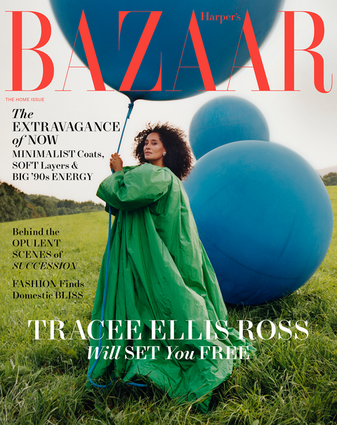 tracee ellis ross poses with a large blue balloon wearing an emerald green balenciaga couture opera coat