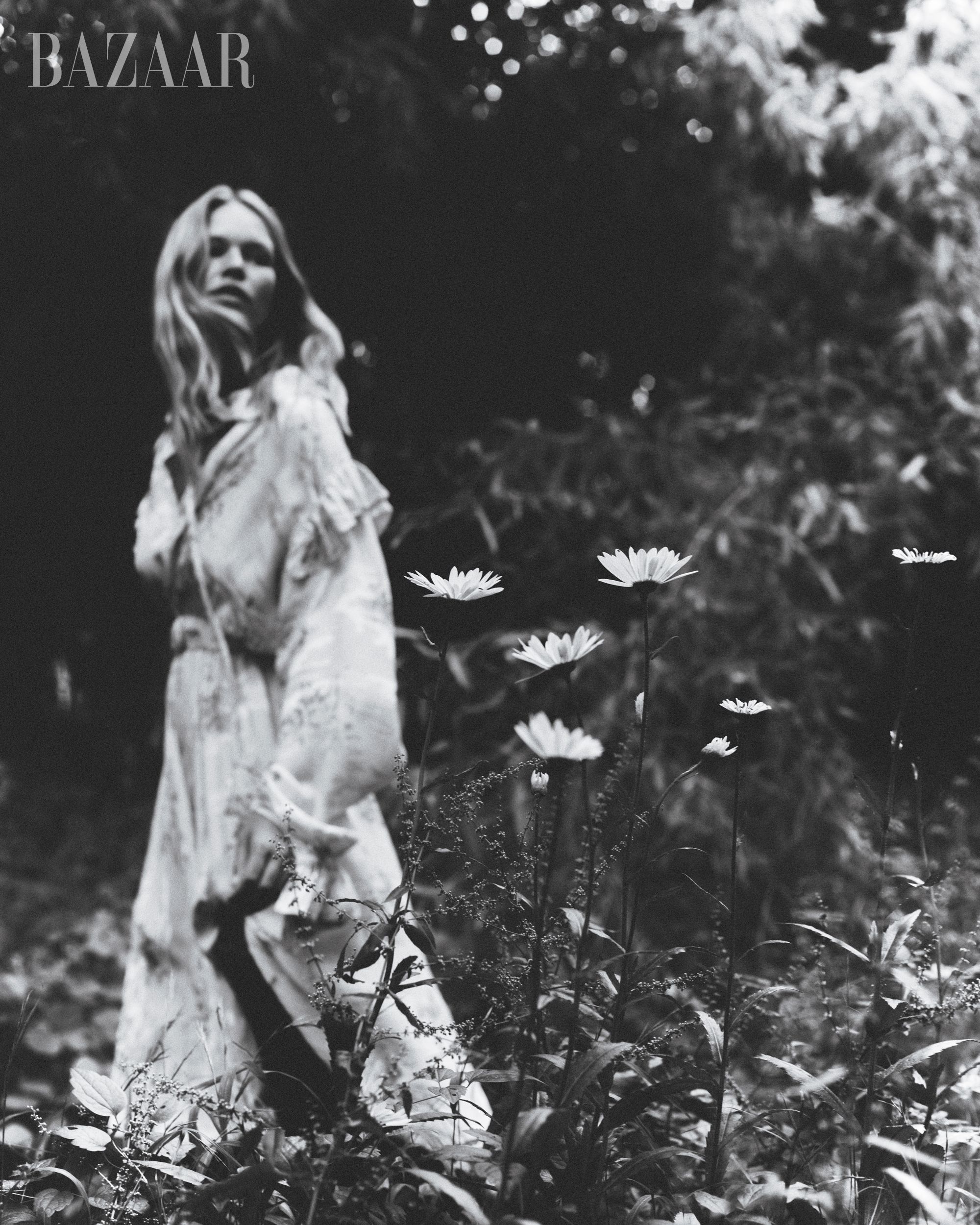 black and white shot of model anna ewers behind flowers