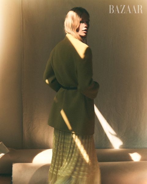 model anna ewer in green coat yellow skirt turning back with sunlight lines