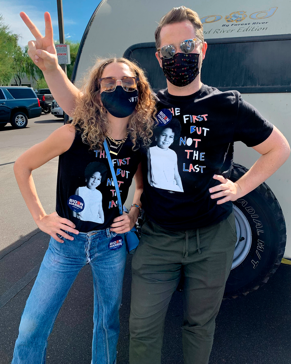two individuals posing with peace signs wearing matching black tshirts with a political message