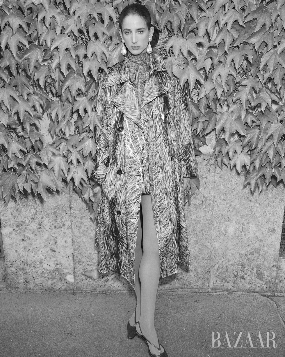 fashion model wearing a stylish coat and heels against a backdrop of ivy