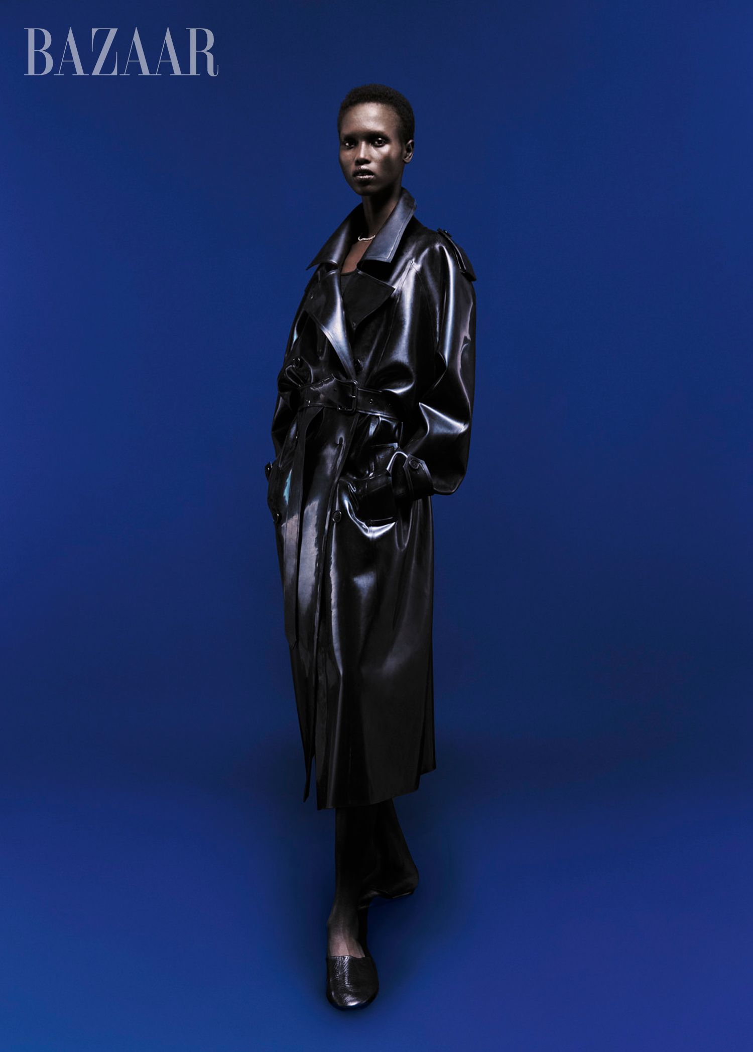 model akway in long black leather coat blue background