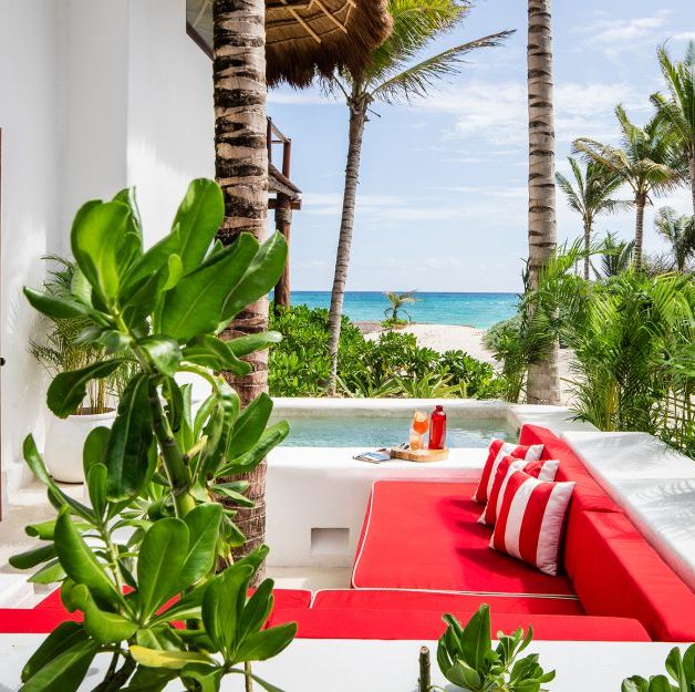 a pool with a red couch and palm trees and a beach