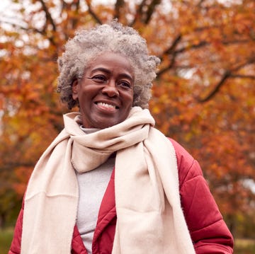 Head And Shoulders Portrait Of Senior Woman On Walk Through Autumn Countryside Against Golden Leaves head and shoulders portrait of senior woman on walk through autumn countryside against golden leaves