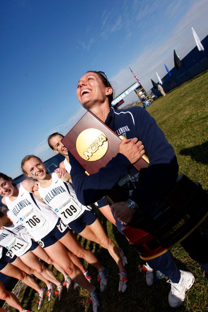 head coach gina procaccio of villanova hugs the championship trophy as the team celebrates with following the division i womens cross country championship in 2009