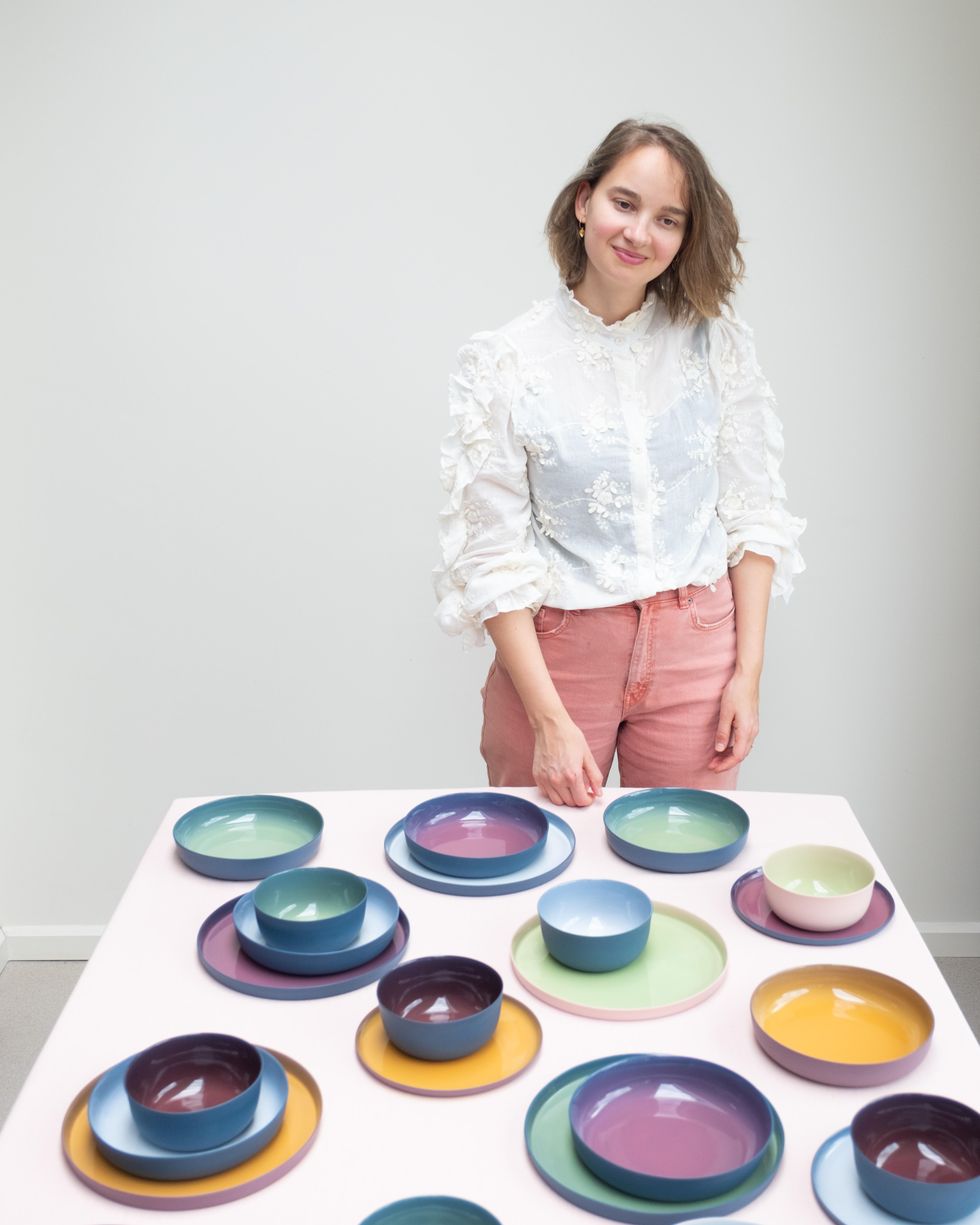 a woman standing next to a table of colorful plates