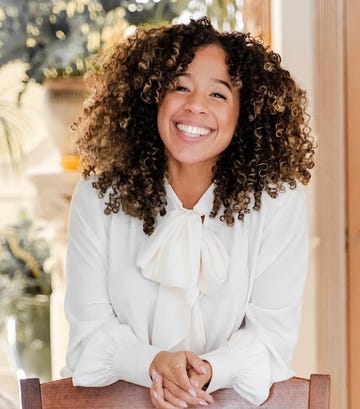 woman sitting at a table wearing a white blouse with a bow tie