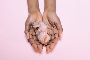 close up of hand holding crystal over white background