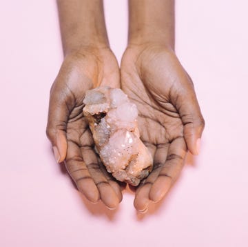 close up of hand holding crystal over white background