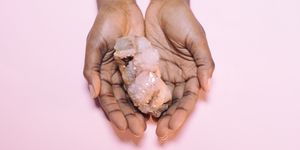 close up of hand holding crystal over white background