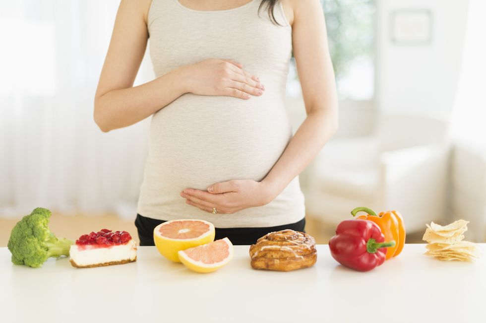 一個懷孕的女生前面擺著食物