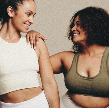 two mixed race women in activewear looking at one another and smiling one has an athletic body shape and the other is curvier
