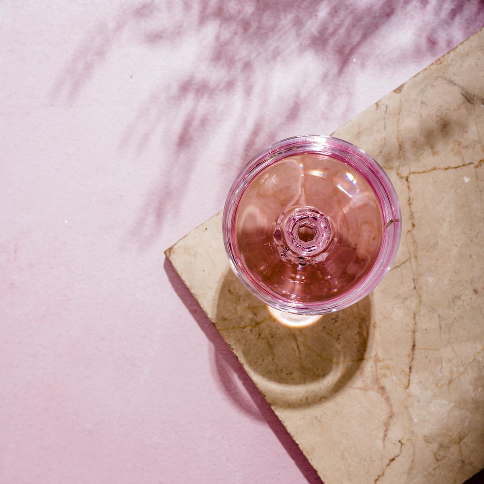 benefits of giving up alcohol, pink champagne in glass on luxury marble table with palm shadow summer beach cocktail party with rose wine alcohol beverage on textured background with tropical plant shade top view