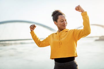 african american mid adult woman exercising outdoors and flexing muscles.