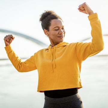 Happy strong woman flexing muscles. african american mid adult woman exercising outdoors and flexing muscles.