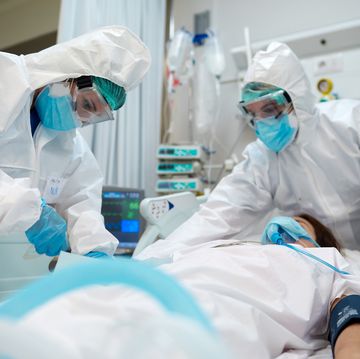 healthcare workers adjusting equipment to a covid patient