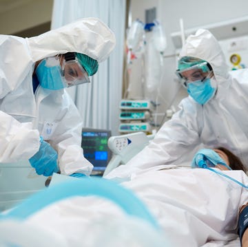 healthcare workers adjusting equipment to a covid patient