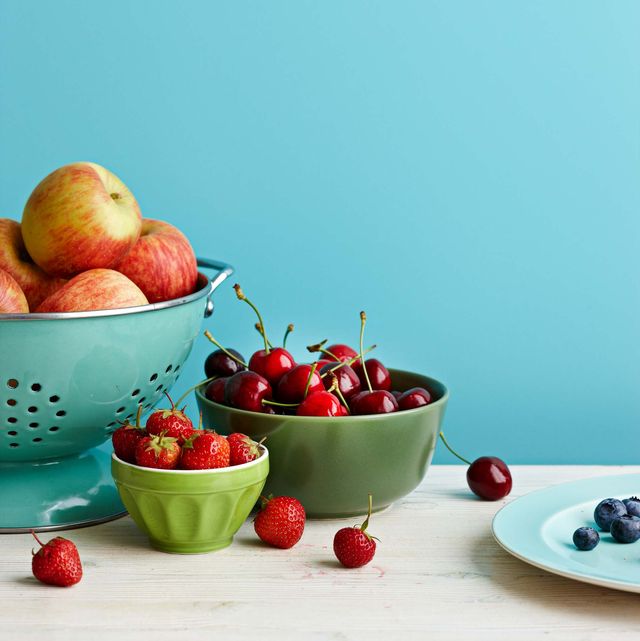 apples, cherries, strawberries, and blueberries in bowls on a table