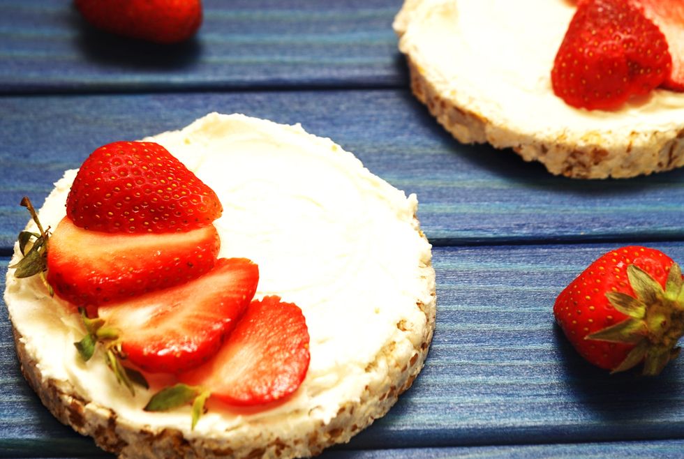 healthy breakfast and a snack of rice bread with red strawberries, with cheese on a blue wooden background