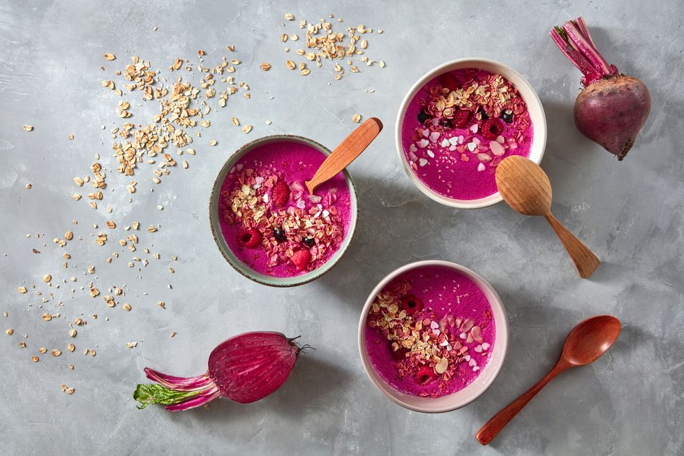 healthy breakfast bowl with beetroot, oat flakes and berry on stone background, flat lay