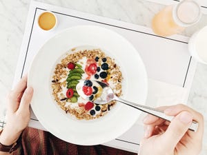 healthy breakfast with granola topped with natural yoghurt, kiwi, raspberry, blueberry, passion fruit served with honey