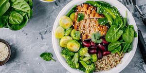 healthy buddha bowl lunch with grilled chicken, quinoa, spinach, avocado, brussels sprouts, broccoli, red beans with sesame seeds